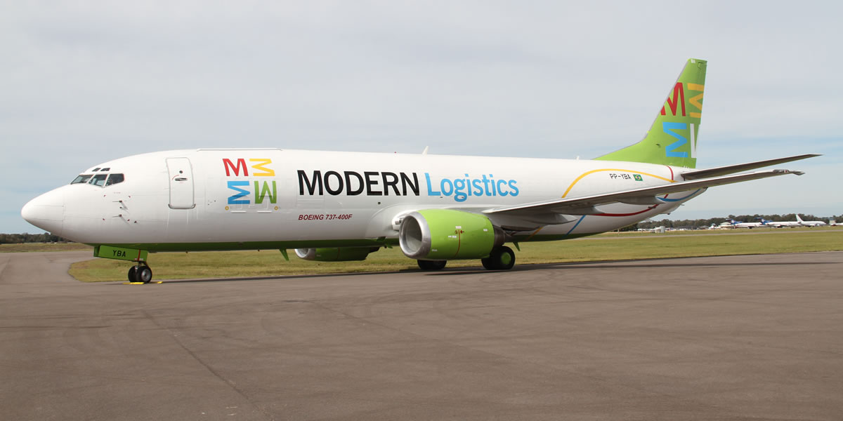 Imagem de uma aeronave Boeing 737-400F da Modern Logistics estacionada no solo, pronta para operação.